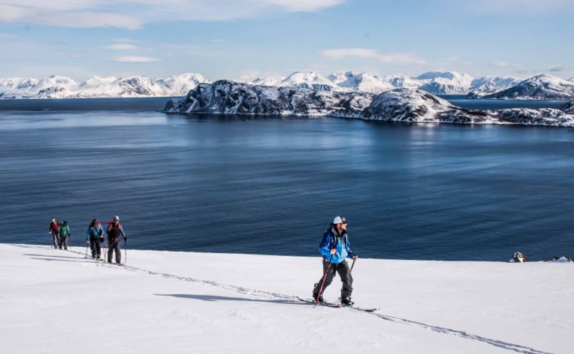 A group skitouring north of Lyngen Alps, amazing contrast with the Norwegian sea in the back